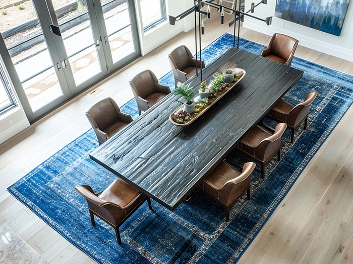 A textured rug sits beneath a large dining table.